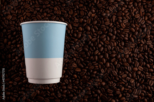Concept - coffee to take away. Disposable paper cup on the background of roasted coffee beans