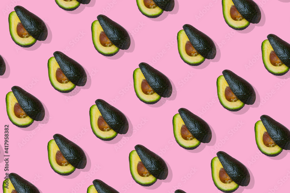 Avocado fruit cut in two halves, trendy  pattern on bright pink background.