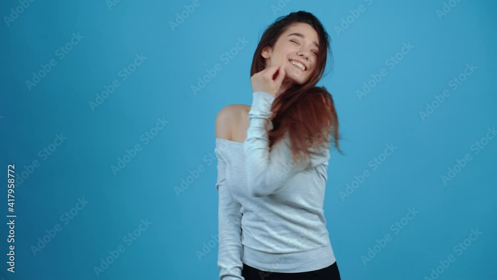 Happy young woman, smiling while arranging her hair Asian with dark hair, dressed in a blue blouse, isolated on a dark blue background in the studio. Lifestyle concept. Portraits with natural emotions Happy young woman, smiling while arranging her hair Asian with dark hair, dressed in a blue blouse, isolated on a dark blue background in the studio. Lifestyle concept. Portraits with natural emotions