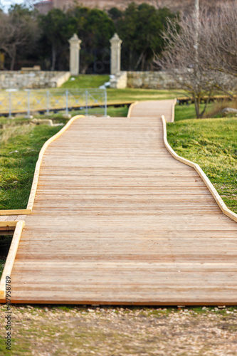 A walkway made of wooden planks in a city park. © kpn1968