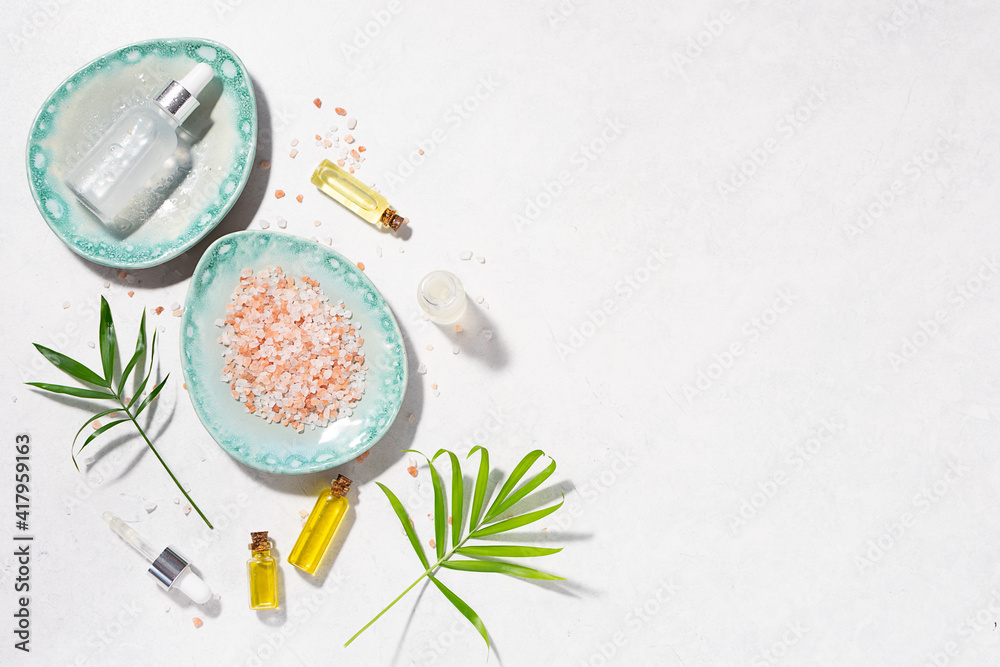Natural skin care serums, Essential oils and cosmetic sea salt with fresh palm leaves on white marble background long banner format. Organic spa products. Natural skin care serums, Essential oils and cosmetic sea salt with fresh palm leaves on white marble background long banner format. Organic spa products.