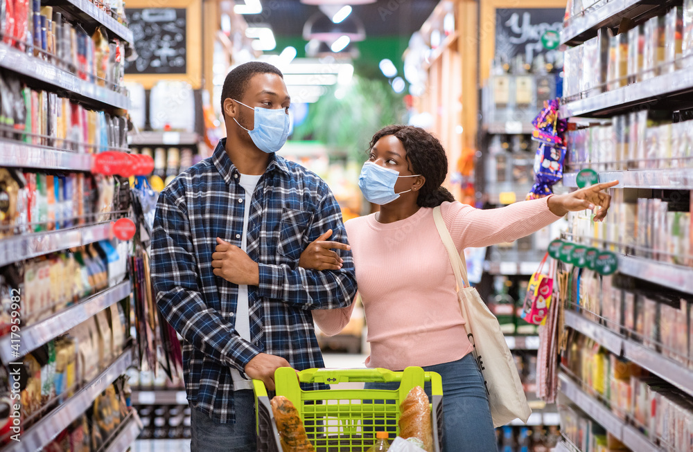 Black family wearing face masks while buying food at supermarket during coronavirus lockdown
