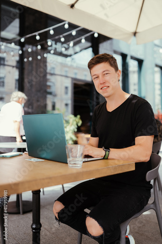 Portrait of man sitting at a table working on a laptop computer.