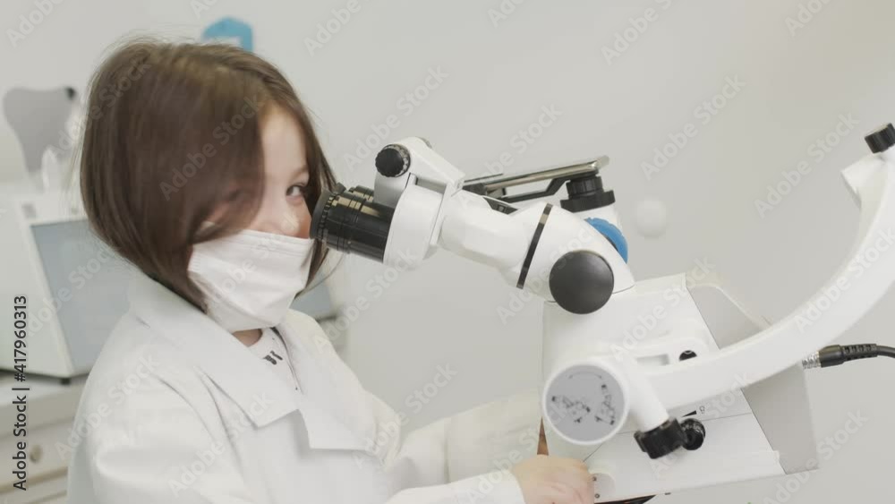 Happy Little child looks through the microscope takes off the mask and smiles without teeth 4K Happy Little child looks through the microscope takes off the mask and smiles without teeth 4K