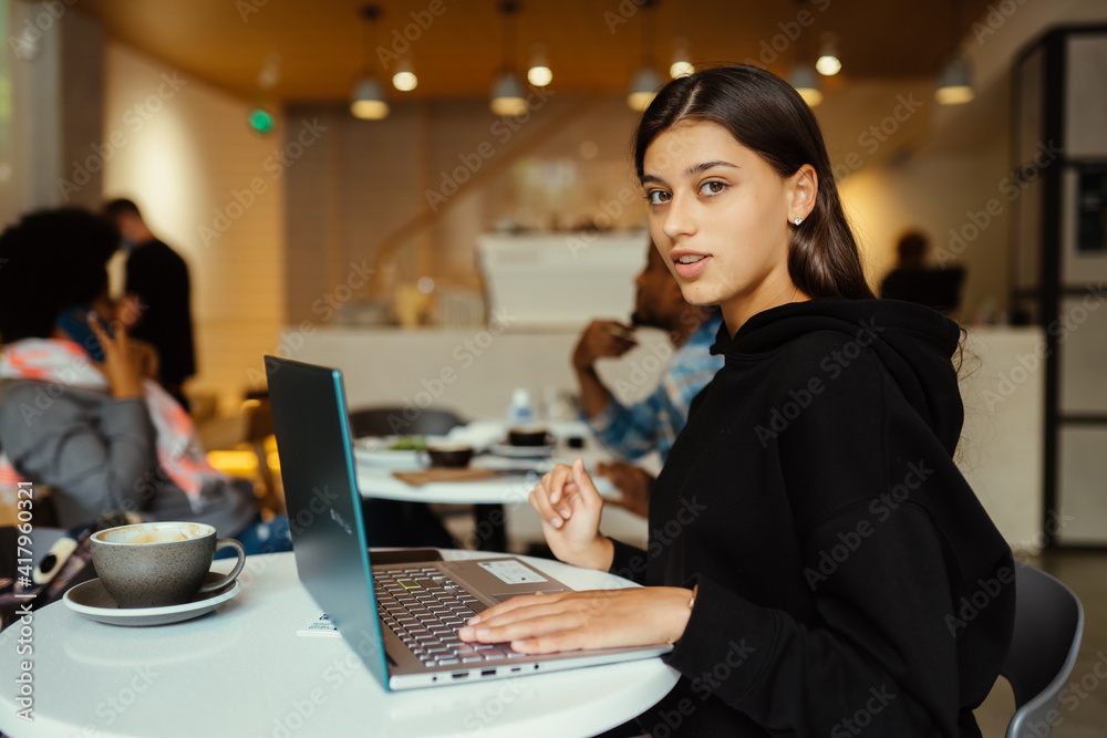 Portrait of female student using net-book while sitting in cafe Portrait of female student using net-book while sitting in cafe