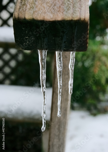 Three icicles hang from a hand rail of a stair