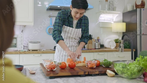 Husband slicing vegetables to prepare breakfast. With a young wife supporting him In a romantic atmosphere