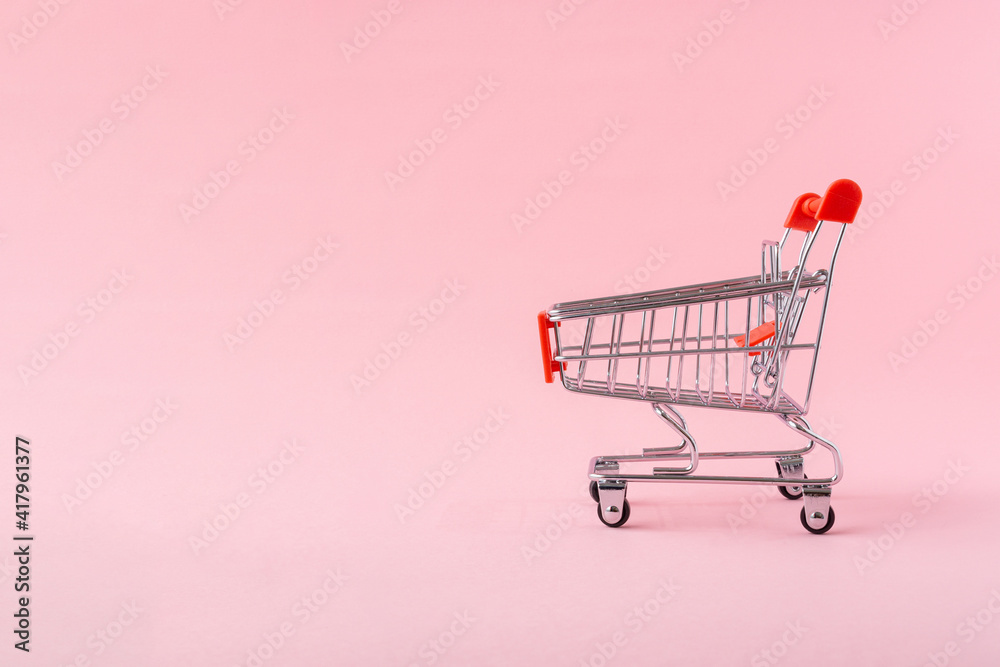 Shopping trolley on light pink background with a copy space. Shopping trolley on light pink background with a copy space.