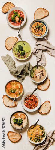 Flat-lay of vegetarian creamy homemade soup with bread slices over white plain table background, top view. Autumn and Winter creamy vegan soups, fall winter vegetarian food menu, comfort food concept