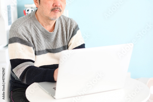 ノートパソコンを操作する高齢者（シニア）の白髪の男性