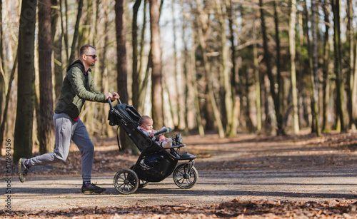 a young male jogging in a park with a baby stroller  © Justyna