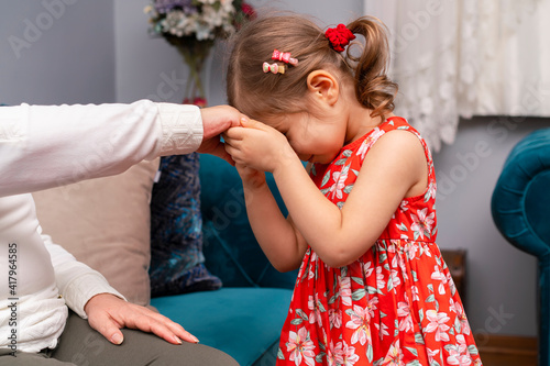 Little baby girl kiss her grandmother's hand during Eid mubarak (Turkish Ramazan or Seker Bayram). Adorable child kiss elderly woman hand to show respect. Cute toddler follow muslim Ramadan traditions
