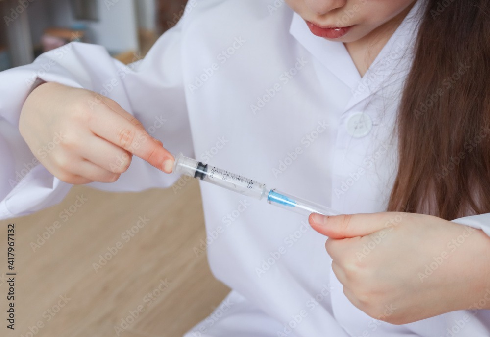 nurse holding syringe.
A child in the uniform of a nurse holds a syringe with a flask in his hands, close-up side view. nurse holding syringe.
A child in the uniform of a nurse holds a syringe with a flask in his hands, close-up side view.