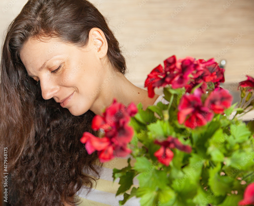Fototapeta premium Adult brunette with blooming plant at home
