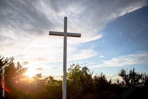 Sunlight bursts behind a mountain top cross of Jesus during golden hour at sunrise on Easter Morning 01