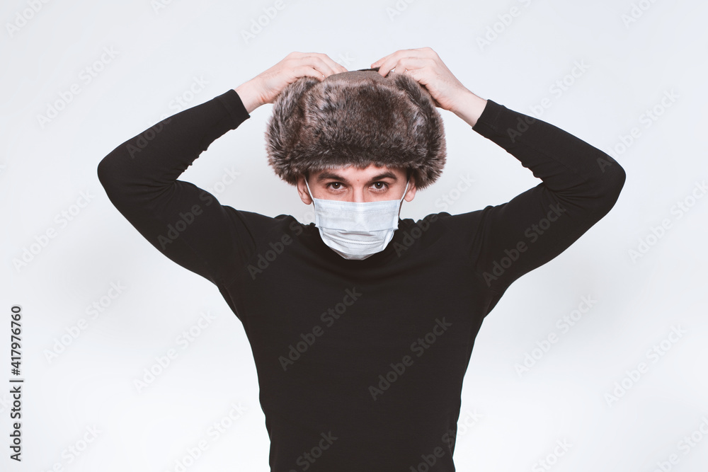 Portrait of a young man in a medical blue mask and wearing winter ...