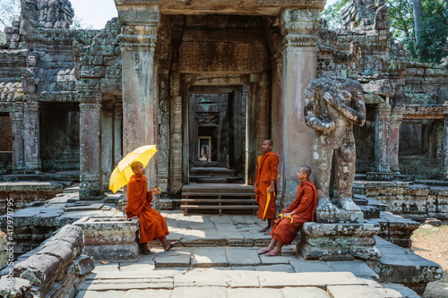 Three monks with umbrella sitting in a temple, Angkor photo