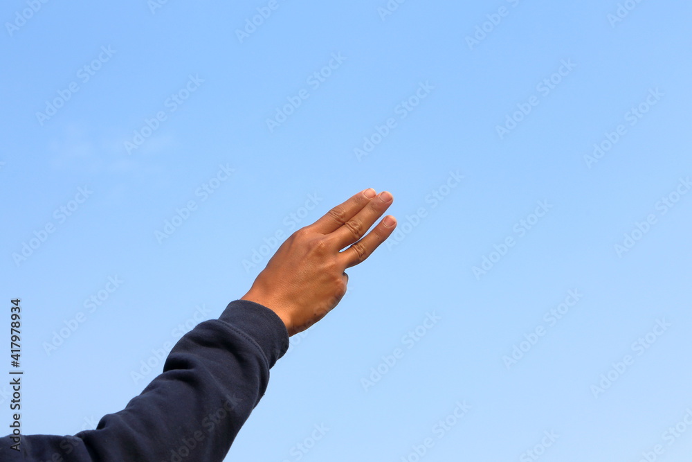 Fototapeta premium Raising three fingers in the sky