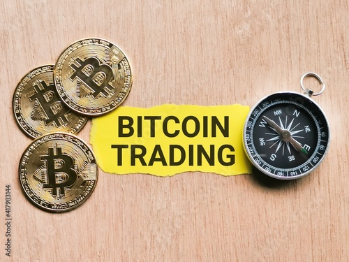 Selective focus phrase Bitcoin Trading written on yellow paper strip with golden bitcoin and compass. Cryptocurrency and finance concept.
