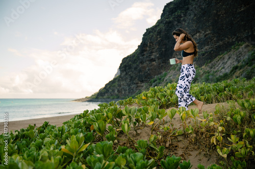 girl walking on beach drinking coffee
