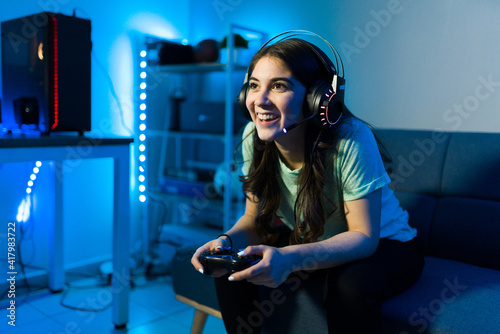 Woman gamer smiling while talking to an online player photo