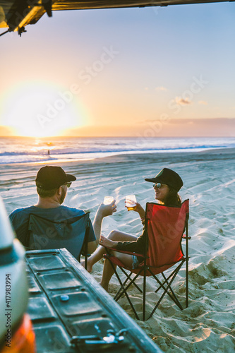 couple drinking cocktail watching sunset on beach