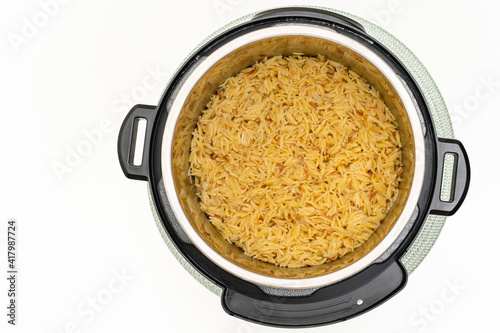 Pasta cooked in Instant Pot. Delicious orzo pasta close up in a pot on white background with copy space, flat lay