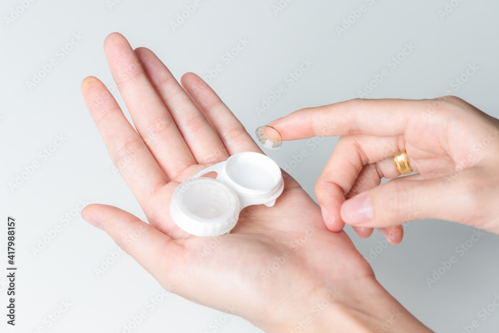 Hands of woman holding contact lenses cases and lens. Hands of woman holding contact lenses cases and lens.