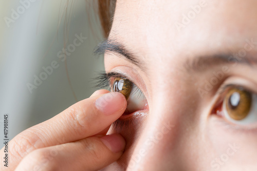 фотографія Close-up shot of young woman wearing or remove contact lens.