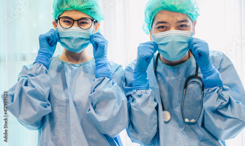 Portrait of funny healthcare workers wearing surgical mask and medical gown before operating in hospital. photo