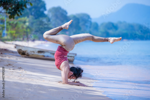 Sport woman yogini scorpion pose practice yoga exercise on the beach sea in relaxing day , yoga is meditation and healthy sport concept