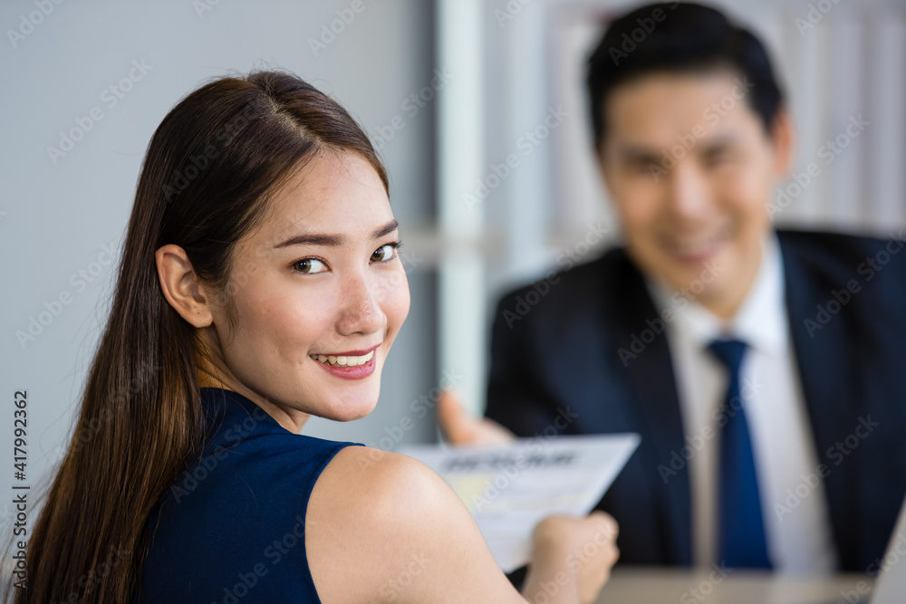 Young Asian man and woman smiling while sitting at table during job interview Young Asian man and woman smiling while sitting at table during job interview