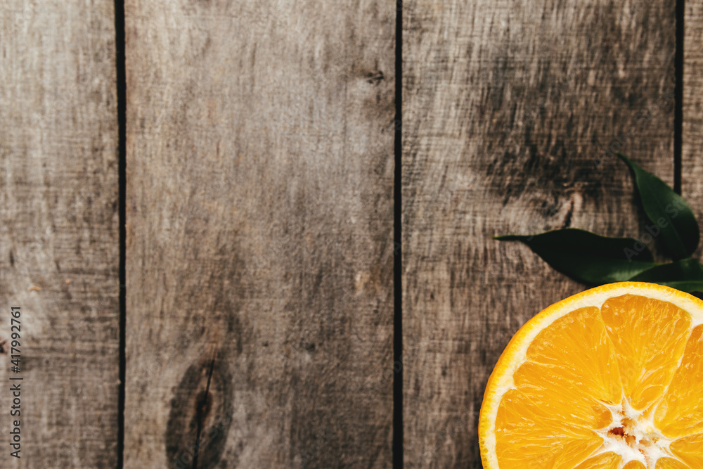 Sliced halves of orange fruit on gray wooden background. Pulp and green leaves Sliced halves of orange fruit on gray wooden background. Pulp and green leaves