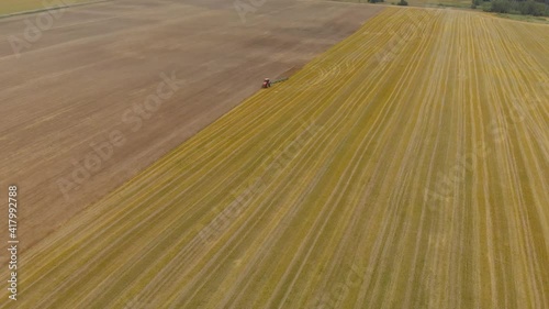 State-of-the-art red tractor with reversible symmetrical multi-plow equipment is piloted unmanned by GPS coordinates in the vast prairie in the spring. Agribusiness in the steppe photo