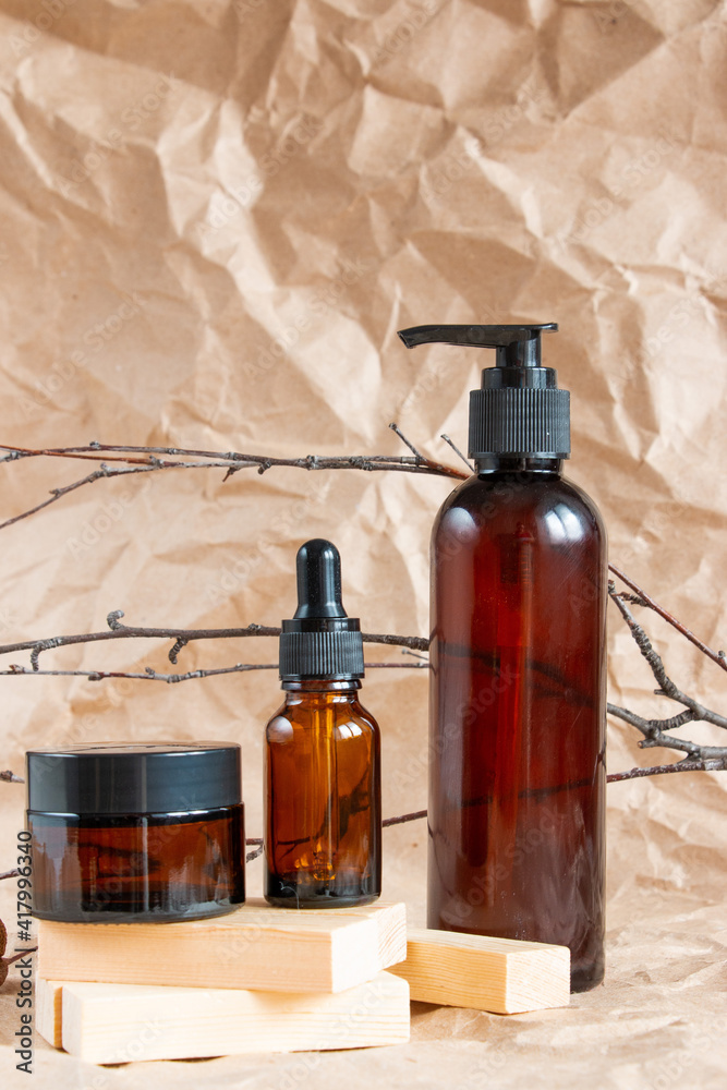 Cometic bottles made of amber glass on crumpled craft paper. Skin care products packaging design. Spa concept. Cometic bottles made of amber glass on crumpled craft paper. Skin care products packaging design. Spa concept.