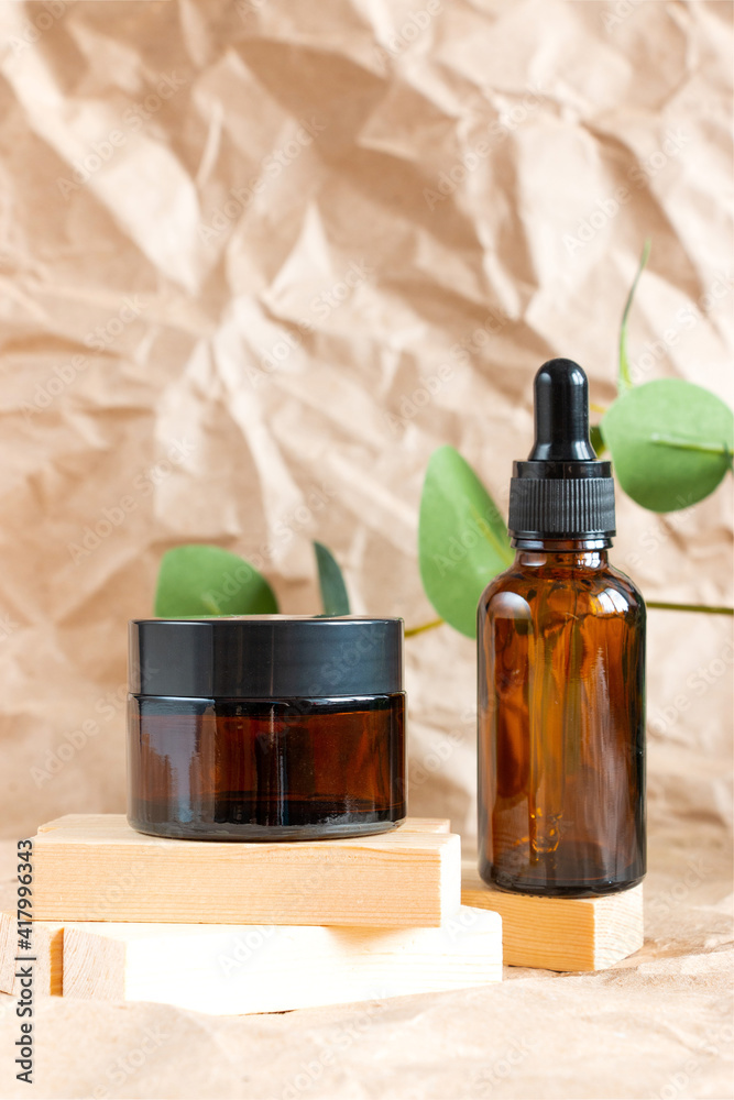 Cometic bottles made of amber glass on crumpled craft paper. Skin care products packaging design. Spa concept. Cometic bottles made of amber glass on crumpled craft paper. Skin care products packaging design. Spa concept.