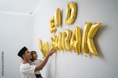 Foto portrait father and daughter muslim decorating eid mubarak letter made of baloon