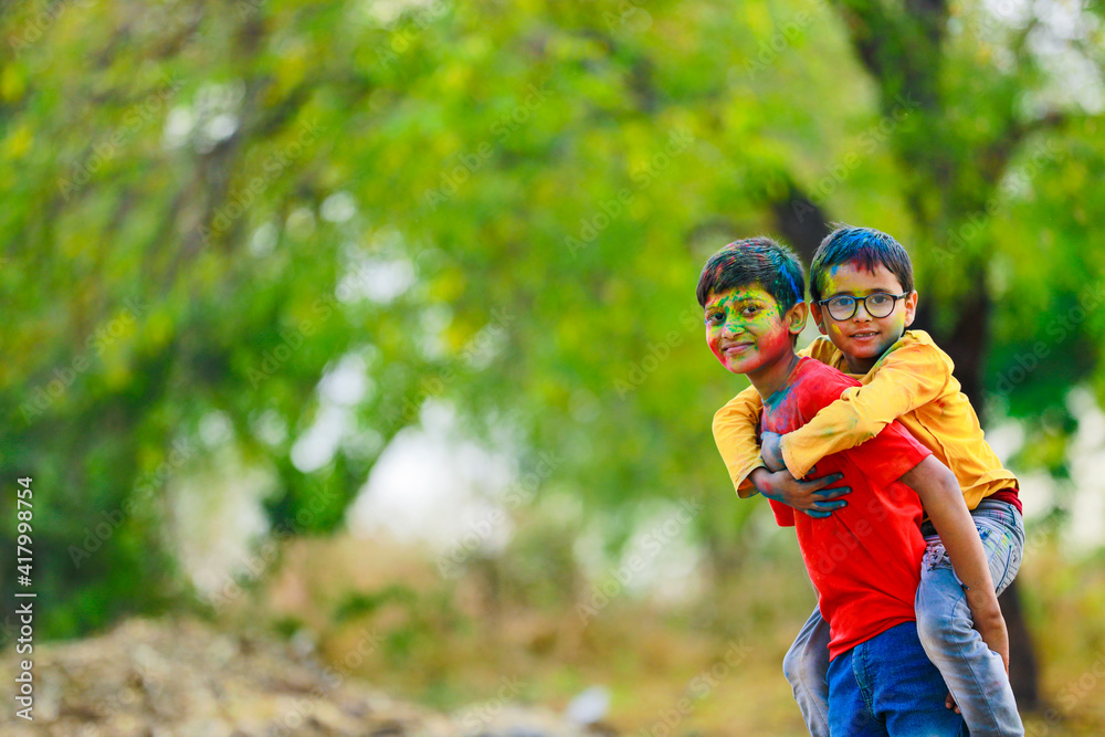 Naklejka premium Cute indian little child playing holi. Holi is colors festival in india