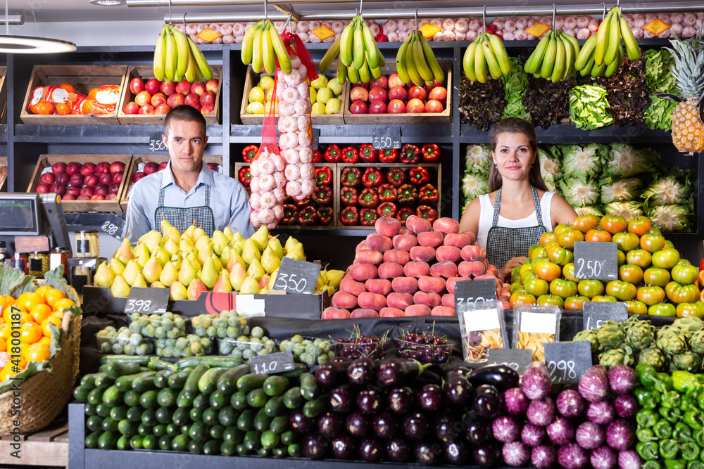 Modern male and female shop assistants in vegetable shop