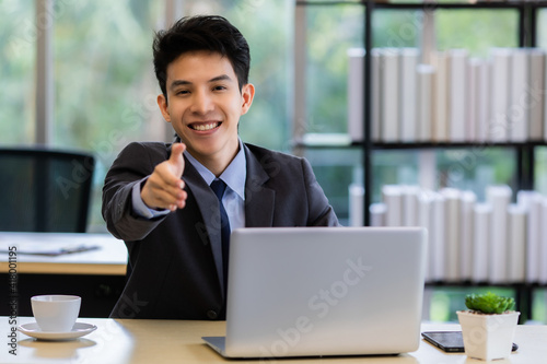 Friendly Asian businessman offering hand to camera