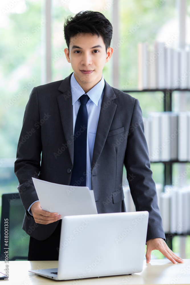 Positive Asian businessman reading papers in office Positive Asian businessman reading papers in office