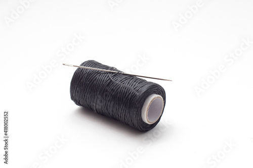 Spool of waxed black sewing threads with neadle.