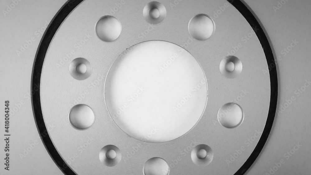 rotation of car brake disk top view. abstract metallic background with metal of silver color with holes rotation of car brake disk top view. abstract metallic background with metal of silver color with holes