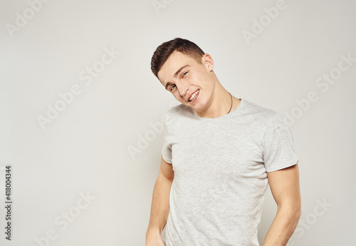 Cheerful handsome man in a white T-shirt gray background