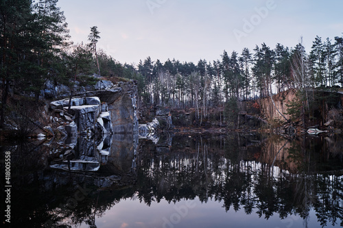 Forest landscape. Guarry and lake with pine trees reflecting in water. photo