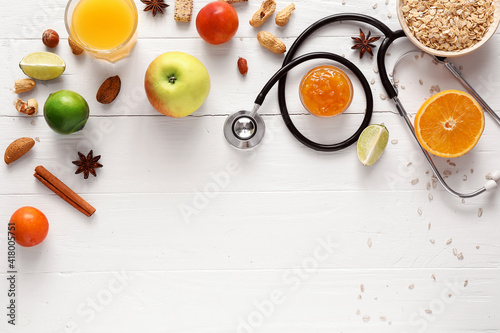 Healthy products, nuts and stethoscope on light background