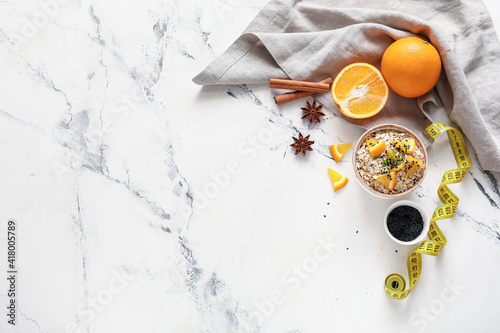 Bowl with raw oatmeal, oranges and chia seeds on light background