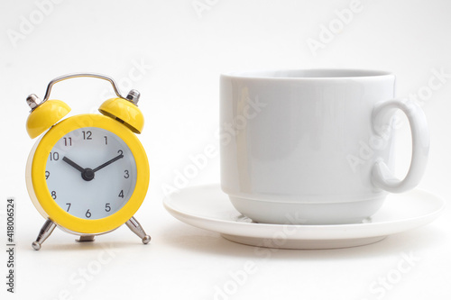 Yellow alarm clock and a white cup of coffee