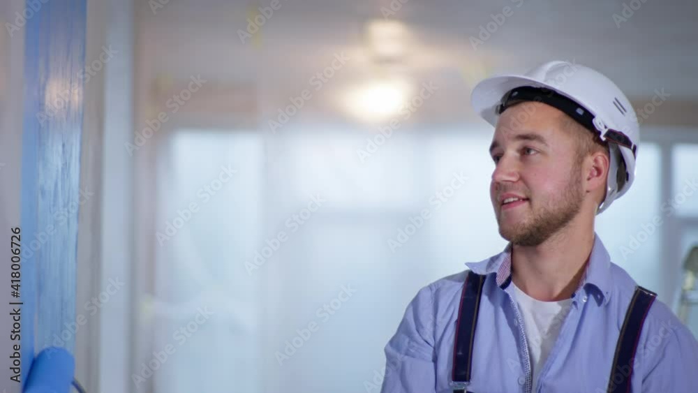 wall painting, young male master painter paints walls by hand using roller brush during indoor renovations and decorating wall painting, young male master painter paints walls by hand using roller brush during indoor renovations and decorating