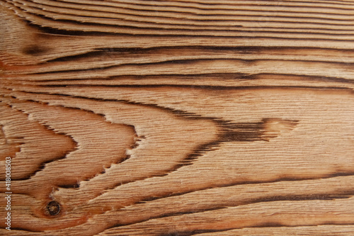 Dark texture of pine board after firing and brushing with a small knot close-up